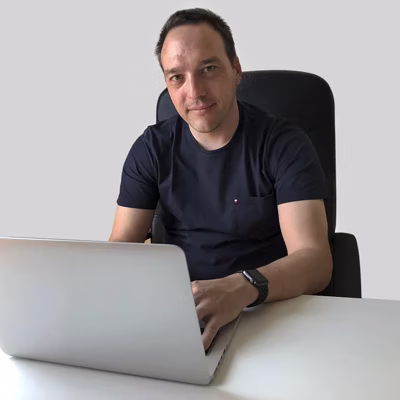 David Prudencio, sentado ante un portátil sobre fondo neutro